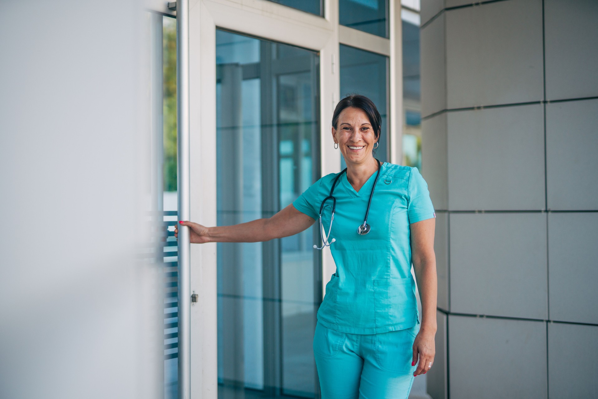 A mature female nurse is entering the hospital and holding